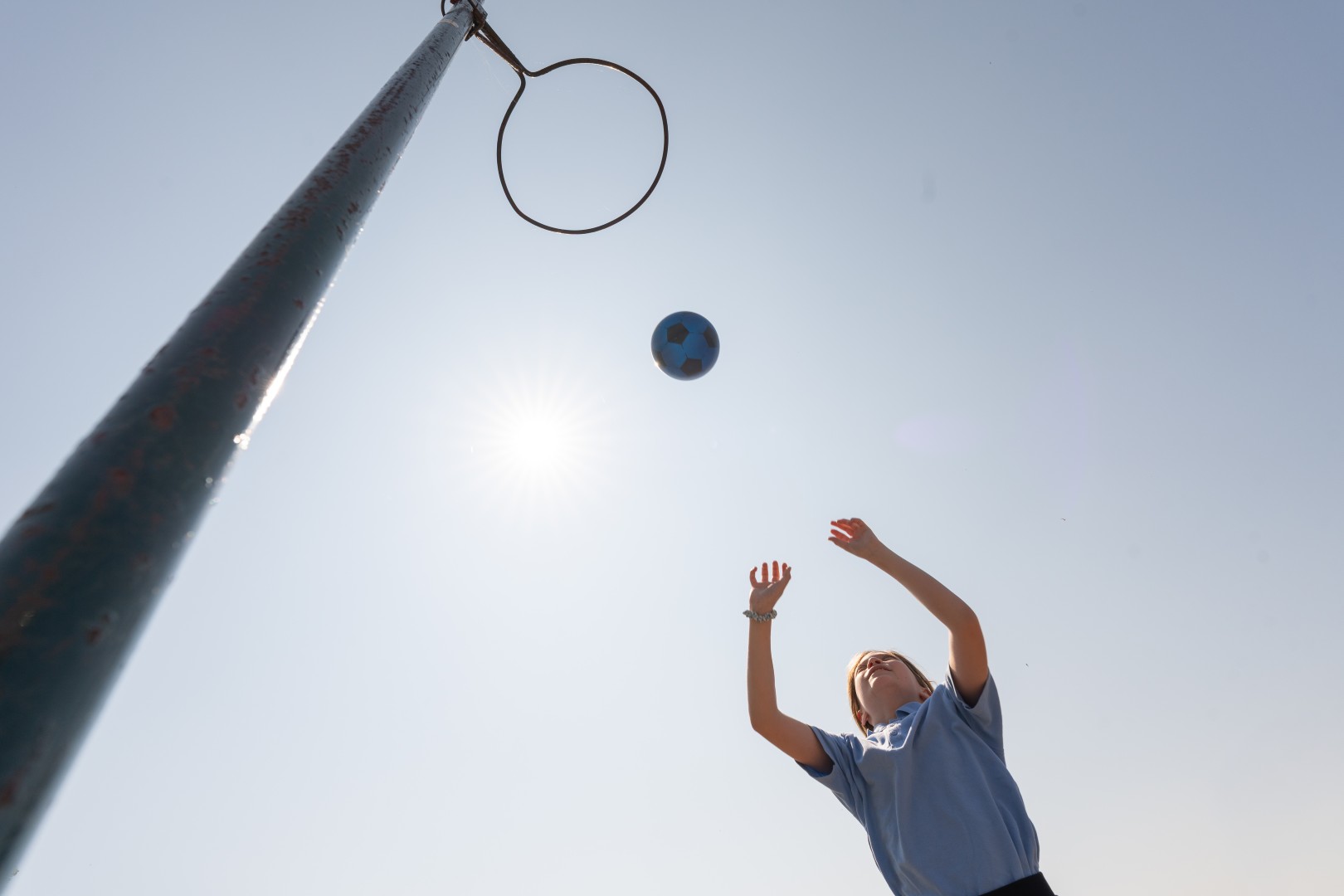 A child throwing a ball through a netball hoop.