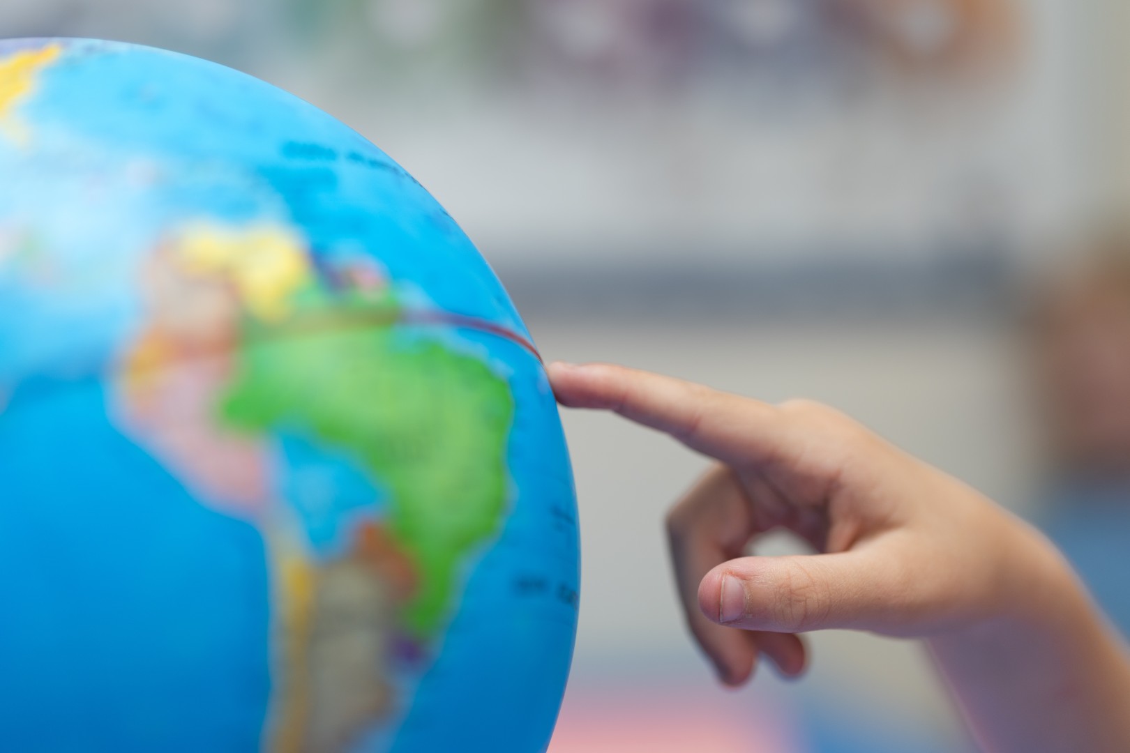 A child's finger pointing to a globe